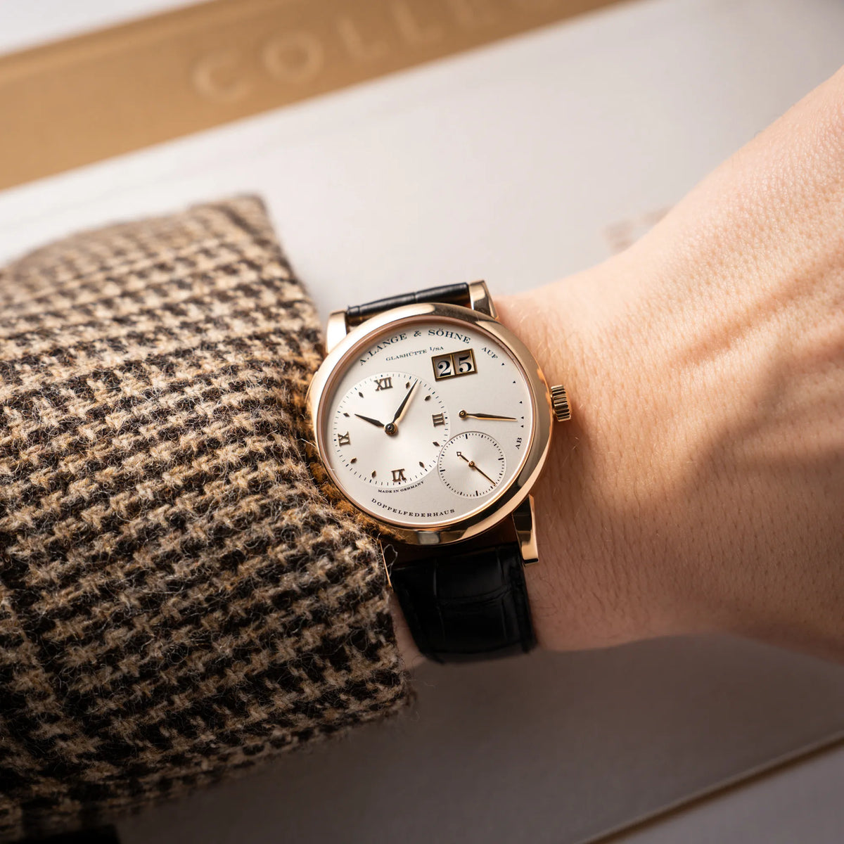 Mann trägt die A. Lange & Söhne Lange 1 der Referenz 101.032 mit 38,5mm-Roségold-Gehäuse und dem für das Modell typische, asymmetrisch angeordnete Zifferblatt mit Großdatum für einen Wristshot an seinem Handgelenk