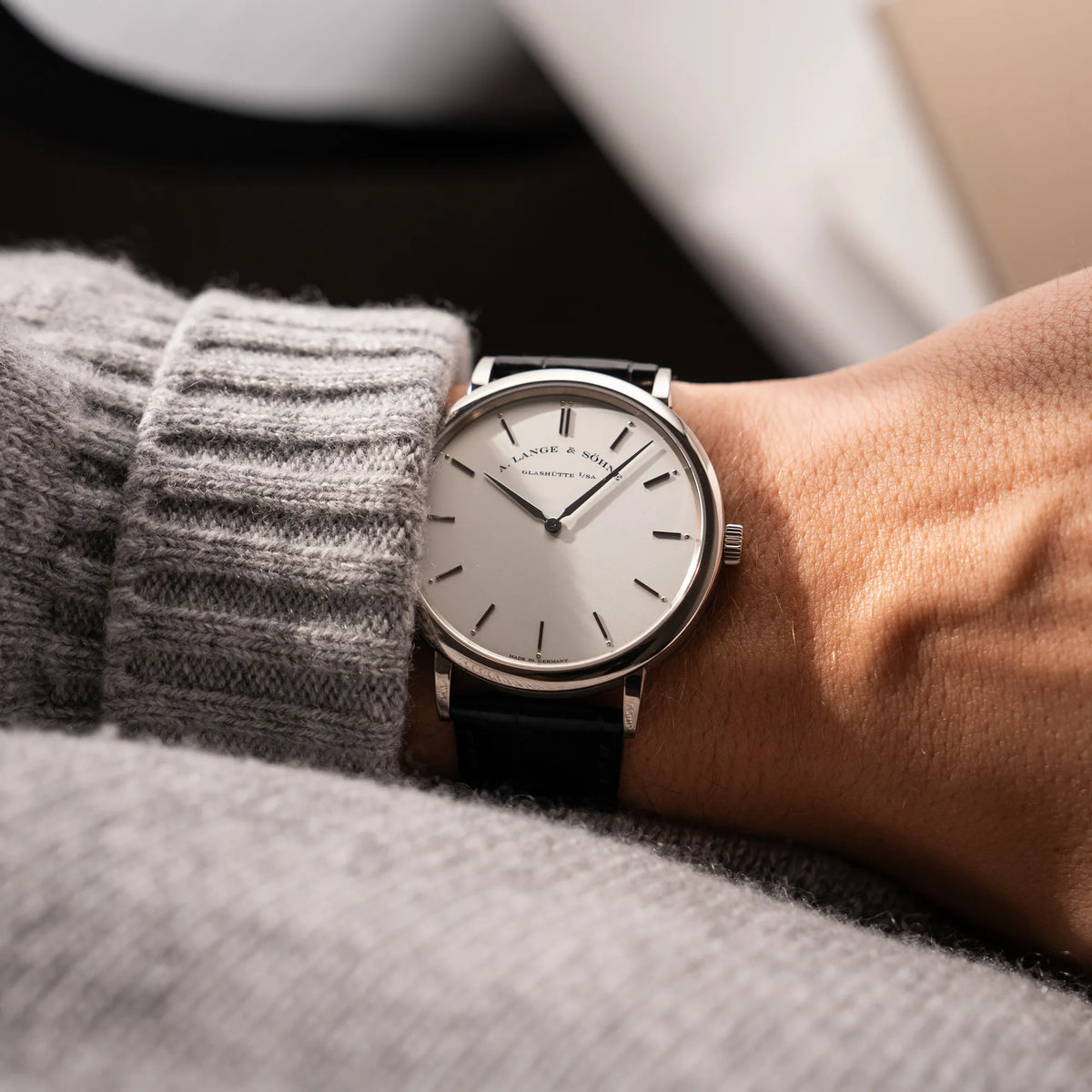 Wristshot mit der A.Lange Söhne Saxonia Thin der Referenz 211.026 im Weißgold-Gehäuse mit weiß-silbernem Zifferblatt am schwarzen Lederarmband an einem Männerhandgelenk