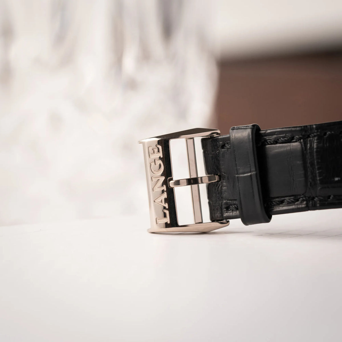 Detailaufnahme der Dornschliesse von der A.Lange Söhne Saxonia Thin der Referenz 211.026 im Weißgold-Gehäuse mit weiß-silbernem Zifferblatt am schwarzen Lederarmband