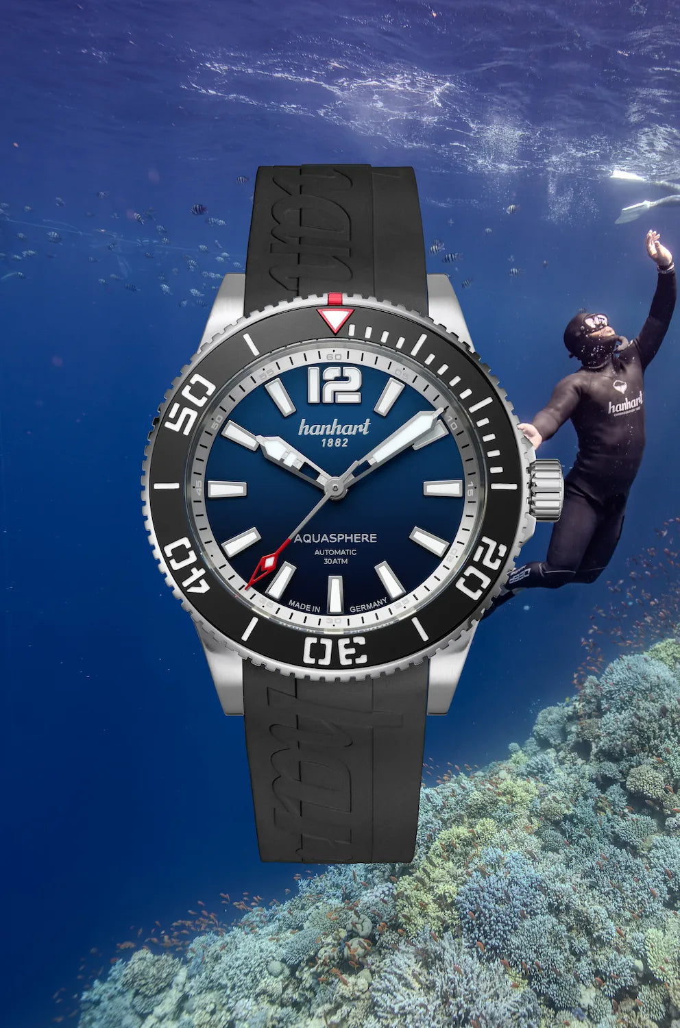 Produktfotografie zeigt die frontale Ansicht der Hanhart Aquasphere mit dem blau-schwarz verlaufenden "Ocean Fade"-Zifferblatt und schwarzem Keramik-Inlay auf der Lünette am schwarzen Kautschuk-Armband mit einem Taucher im Meer als Hintergrund