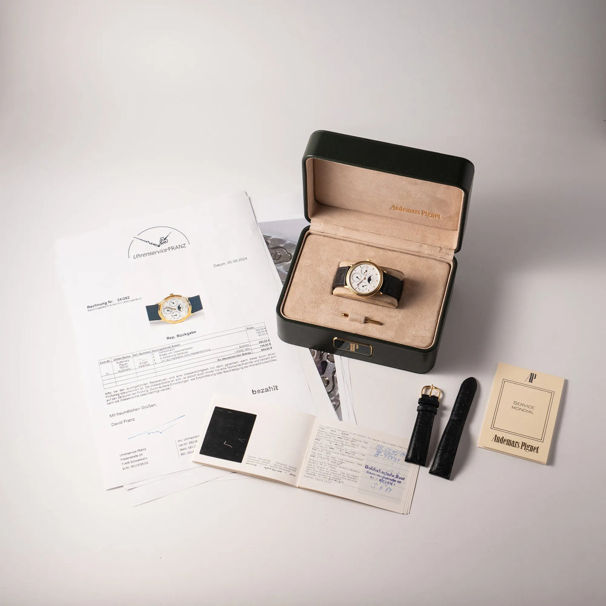 Audemars Piguet Quantième Perpétual der Referenz 5548BA mit 36mm-Gelbgold-Gehäuse und weißem Zifferblatt an einem schwarzen Lederband zusammen mit dem Lieferumfang, bestehend aus Box, gelbgoldenen Stellstift, Service-Beleg und original Papieren
