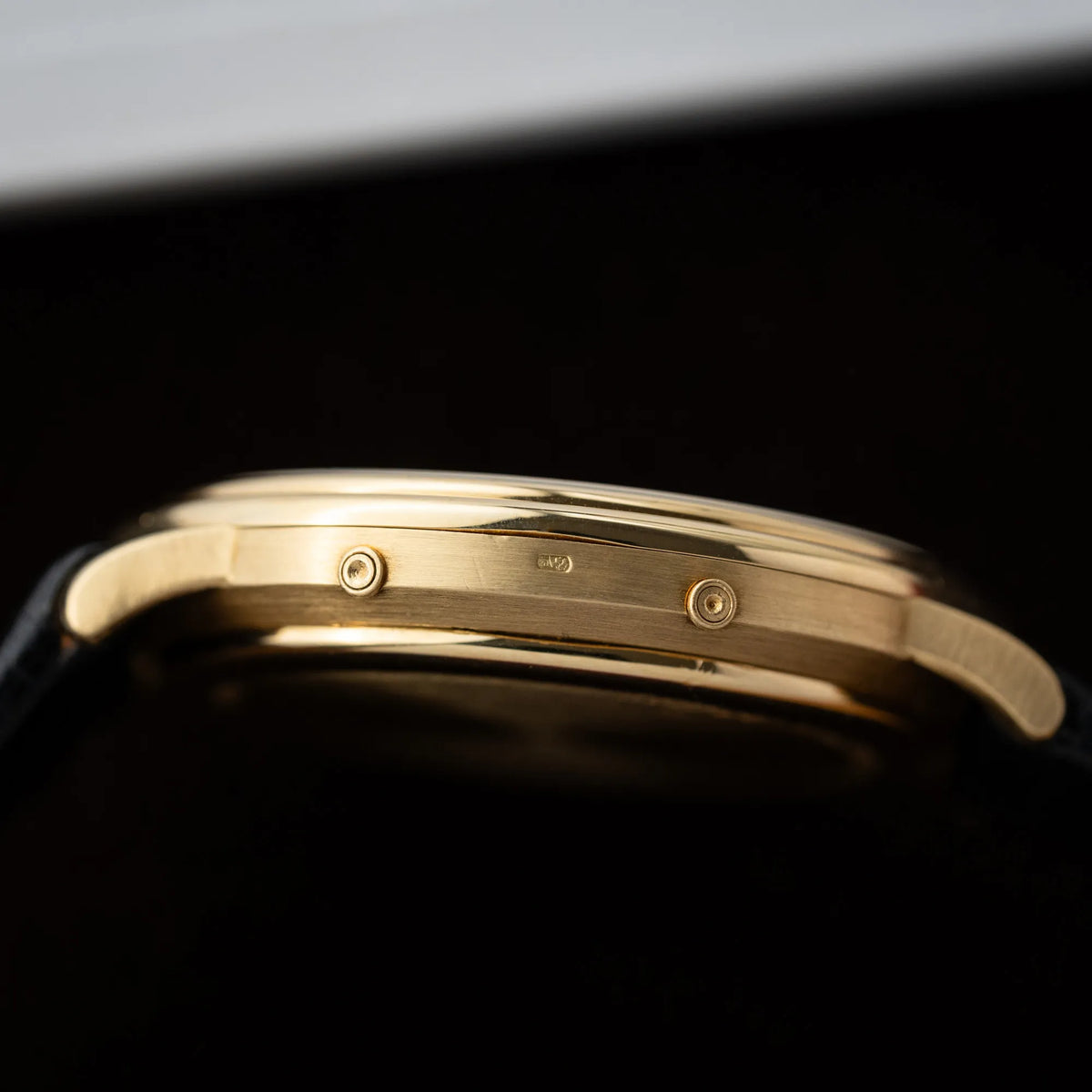 Seitliche Gehäuseflanke der Audemars Piguet Quantième Perpétual der Referenz 5548BA mit 36mm-Gelbgold-Gehäuse und weißem Zifferblatt an einem schwarzen Lederband