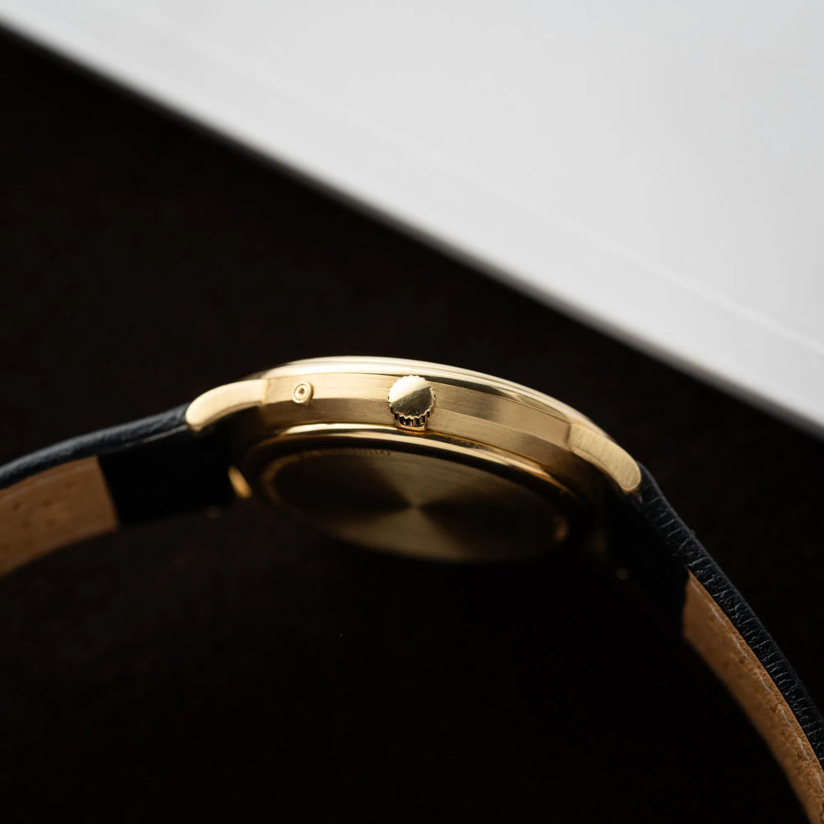 Seitliche Gehäuseflanke mit Blick auf die Aufzugskrone der Audemars Piguet Quantième Perpétual der Referenz 5548BA mit 36mm-Gelbgold-Gehäuse und weißem Zifferblatt an einem schwarzen Lederband