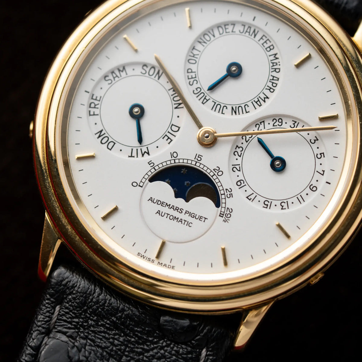 Detailaufnahme der Audemars Piguet Quantième Perpétual der Referenz 5548BA mit 36mm-Gelbgold-Gehäuse und weißem Zifferblatt an einem schwarzen Lederband