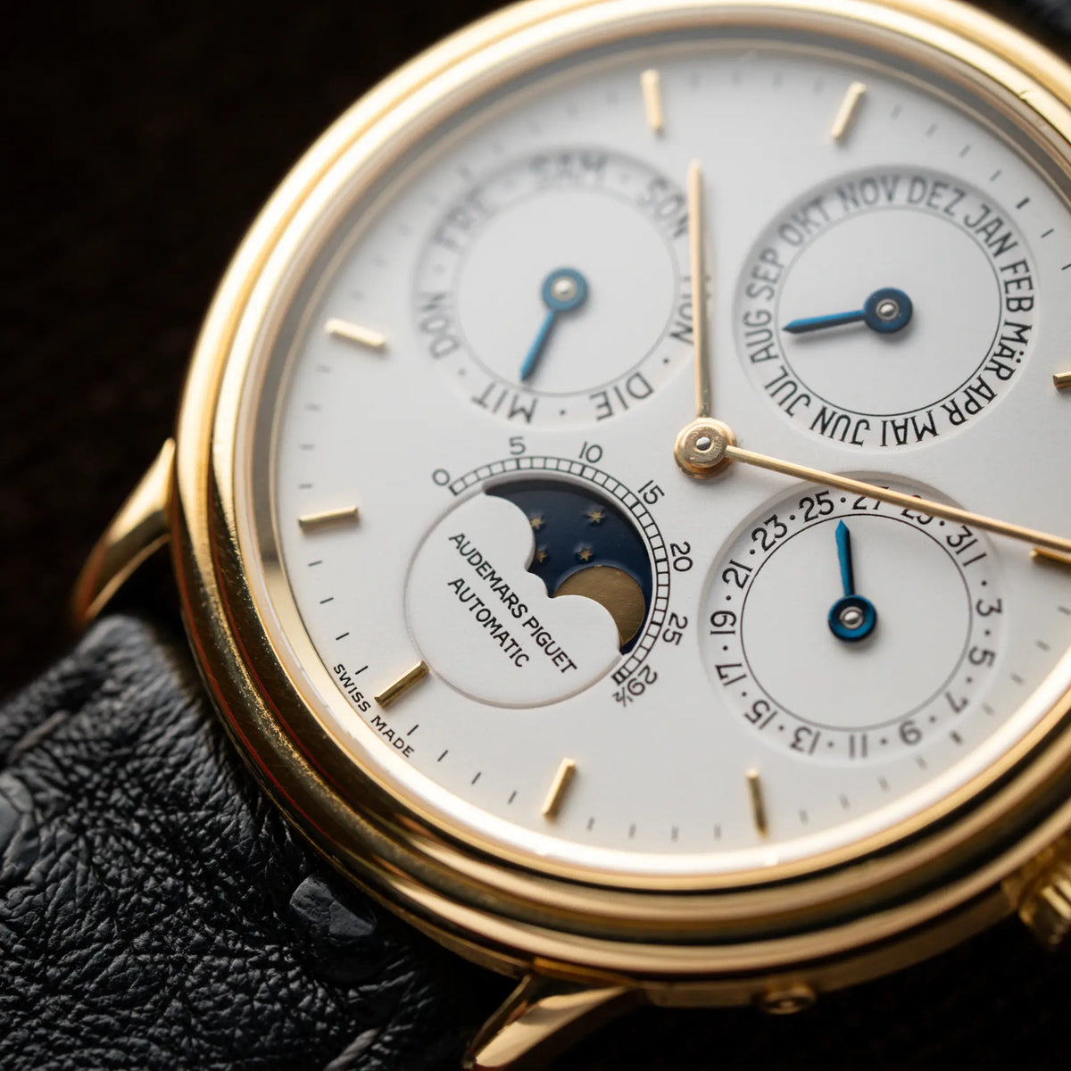 Detailaufnahme der Audemars Piguet Quantième Perpétual der Referenz 5548BA mit 36mm-Gelbgold-Gehäuse und weißem Zifferblatt an einem schwarzen Lederband mit Fokus auf der Mondphase-Anzeige