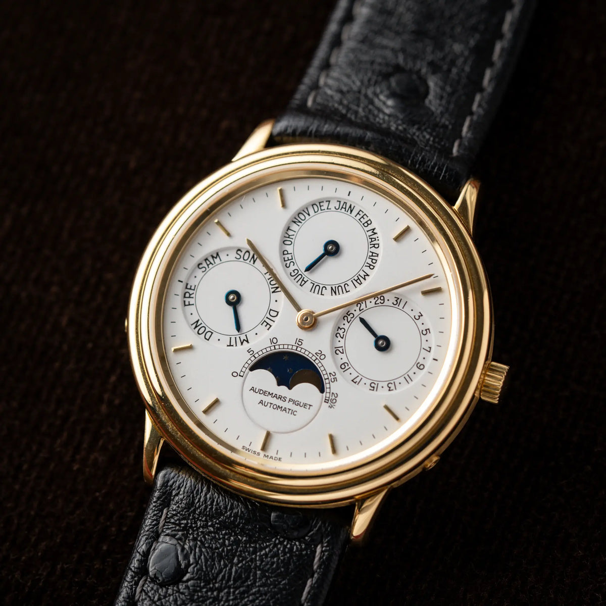 Produktfotografie als Titelbild der Audemars Piguet Quantième Perpétual der Referenz 5548BA mit 36mm-Gelbgold-Gehäuse und weißem Zifferblatt an einem schwarzen Lederband