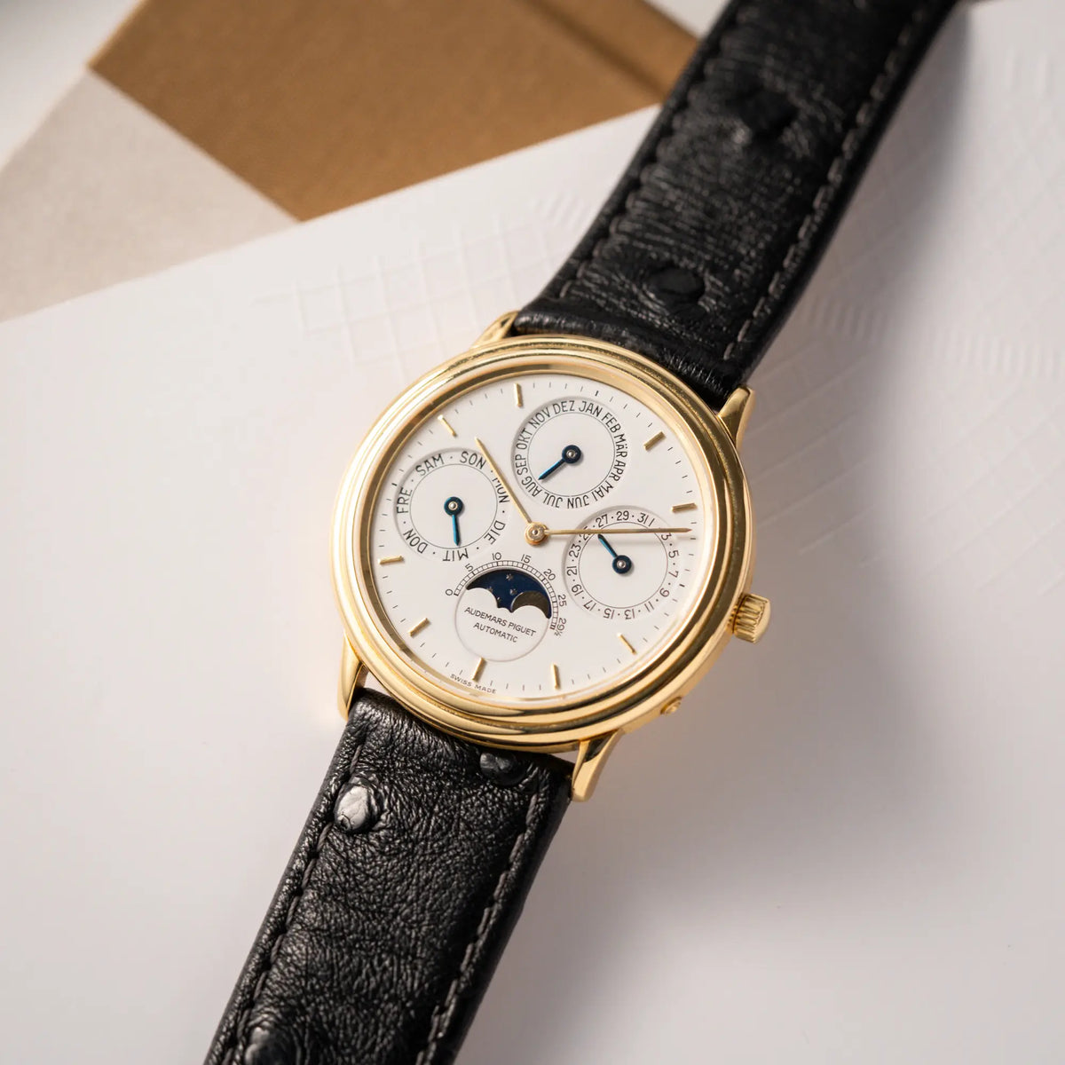 Produktfotografie der Audemars Piguet Quantième Perpétual der Referenz 5548BA mit 36mm-Gelbgold-Gehäuse und weißem Zifferblatt an einem schwarzen Lederband