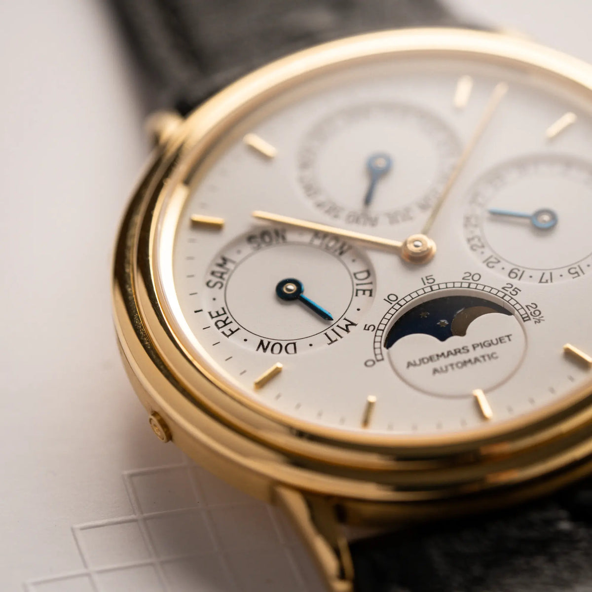 Detailaufnahme der Audemars Piguet Quantième Perpétual der Referenz 5548BA mit 36mm-Gelbgold-Gehäuse und weißem Zifferblatt an einem schwarzen Lederband mit Fokus auf der Wochentagsanzeige