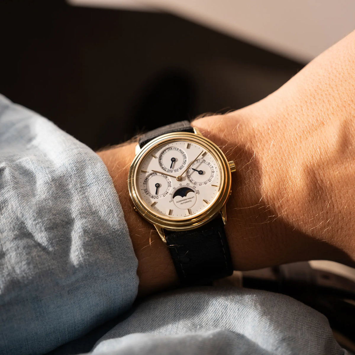 Wristshot mit der Audemars Piguet Quantième Perpétual der Referenz 5548BA mit 36mm-Gelbgold-Gehäuse und weißem Zifferblatt an einem schwarzen Lederband