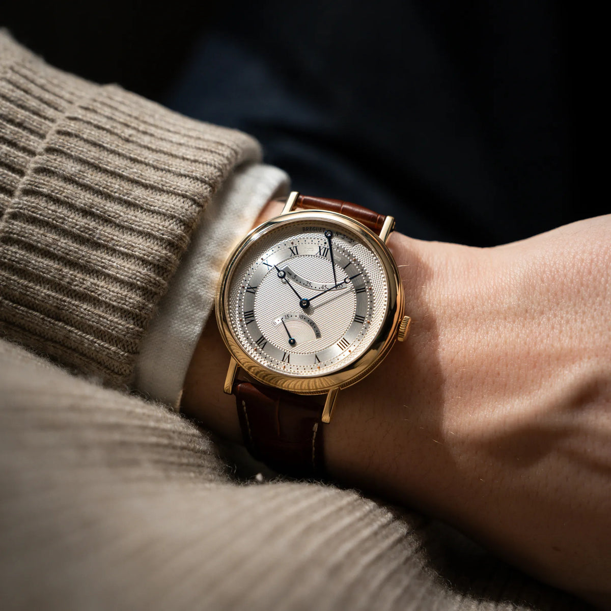 Wristshot mit dem der gelbgoldenen Breguet Armbanduhr des Models Classic Retrograde 5207 am braunen Lederband