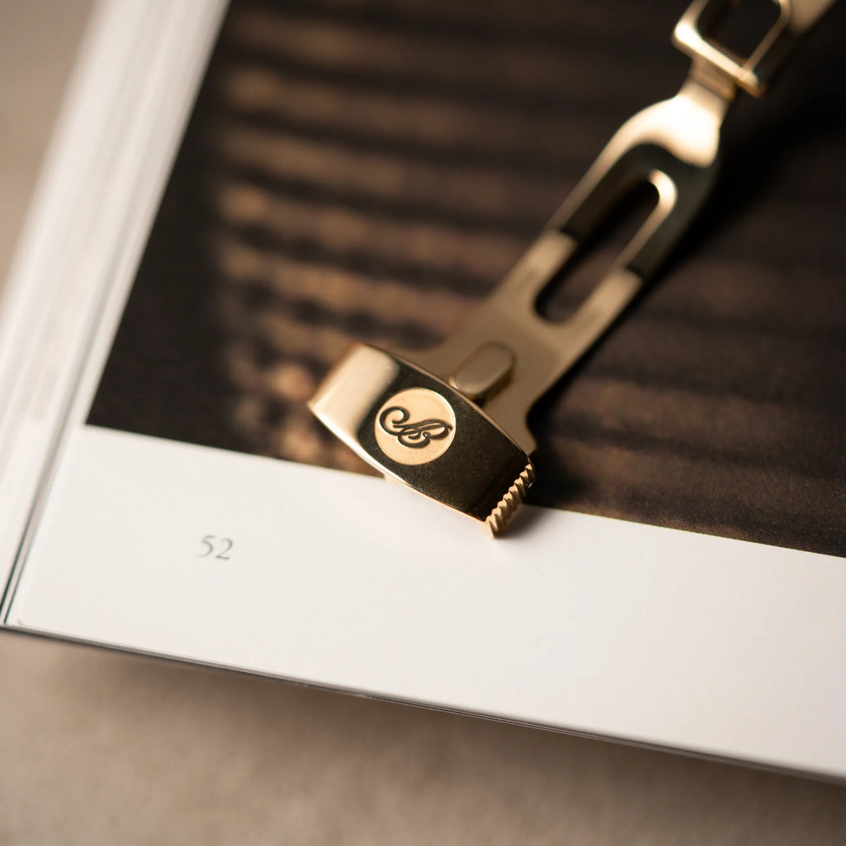 Makroaufnahme des Breguet-Logos auf der gelbgoldenen Schliesse der Breguet Armbanduhr des Models Classic Retrograde 5207 am braunen Lederband