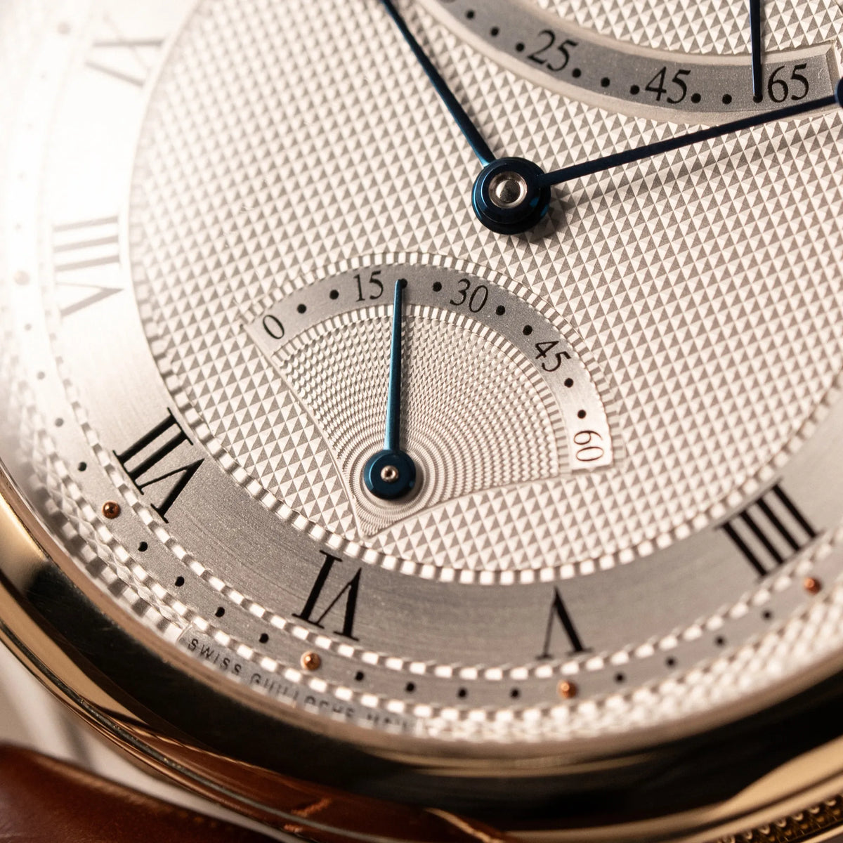 Makroaufnahme der Retrograde Anzeige auf 6 Uhr der gelbgoldenen Breguet Armbanduhr des Models Classic 5207 am braunen Lederband