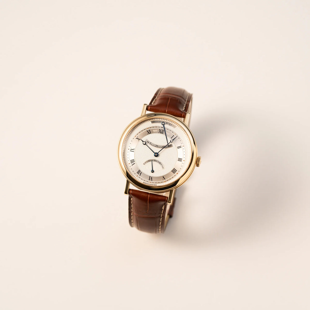 Leicht schräge Ansicht der gelbgoldenen Breguet Armbanduhr des Models Classic Retrograde 5207 am braunen Lederband