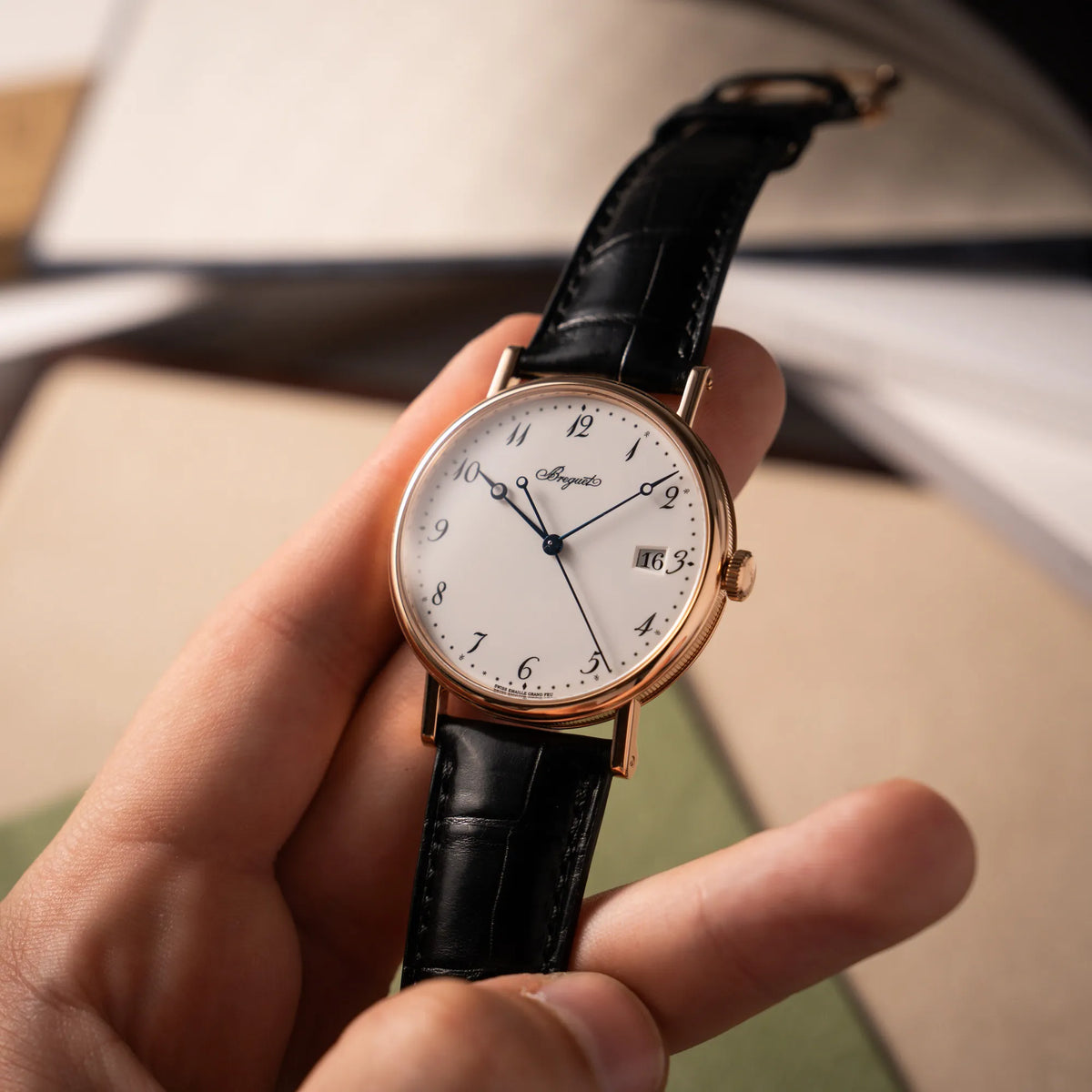 Mann hält die Breguet Classique 5177 in Roségold mit weißem Emaille-Zifferblatt in seiner Hand