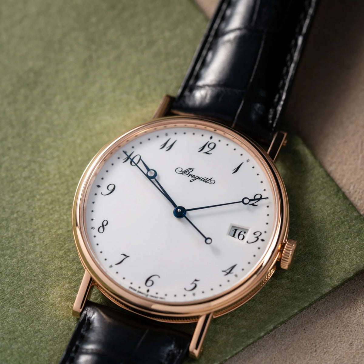 Produktfotografie der Breguet Classique 5177 in Roségold mit weißem Emaille-Zifferblatt auf olivgrünem Hintergrund