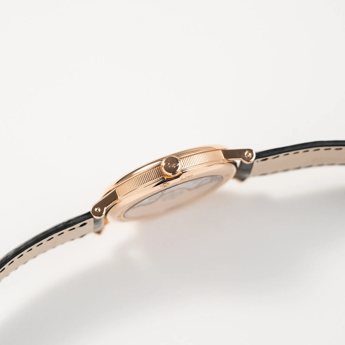 Seitliches, kenneliertes Gehäuse der Breguet Classique 5177 in Roségold mit weißem Emaille-Zifferblatt mit Blick auf die Aufzugskrone