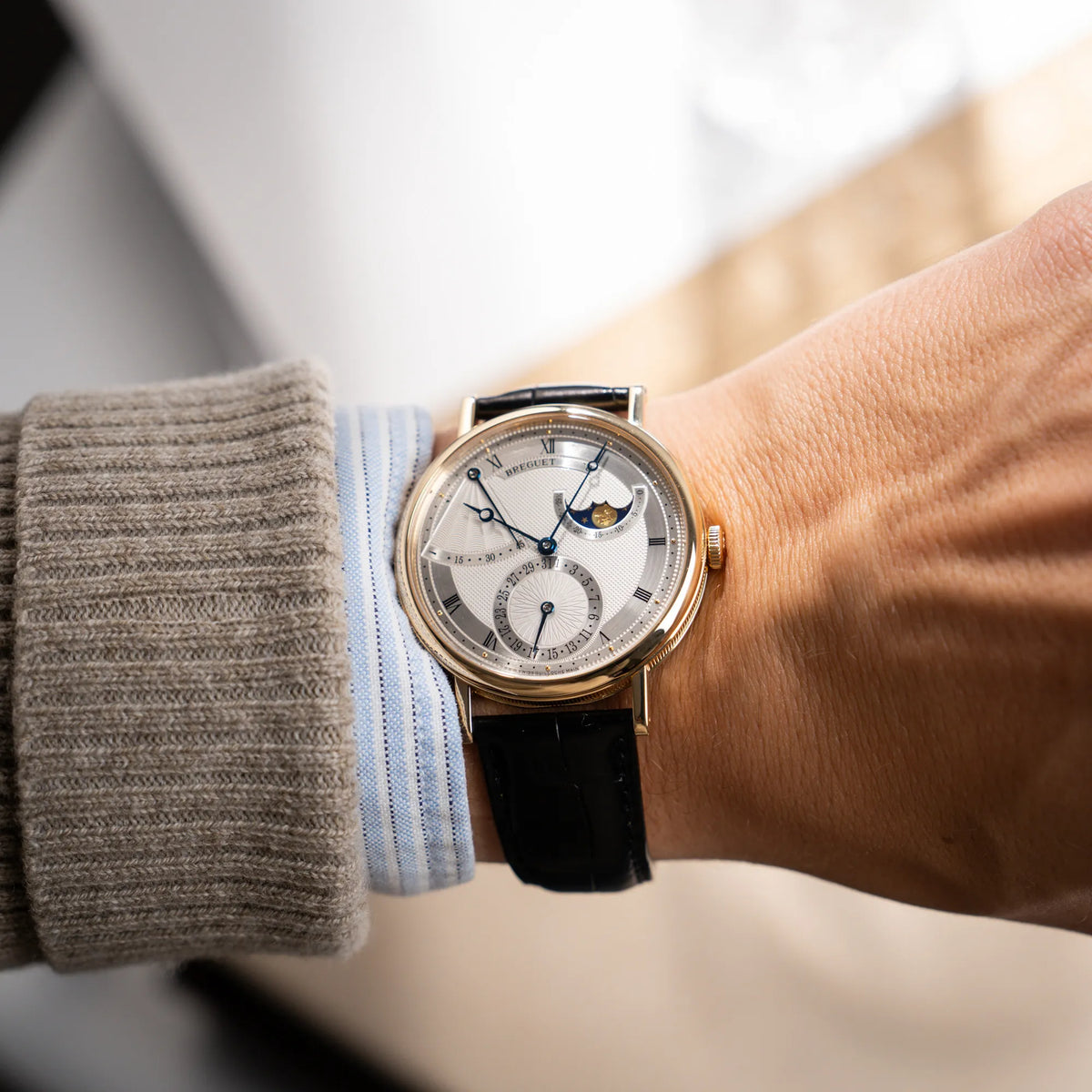 Wristshot mit der Breguet Classique 7137BA mit einem Gelbgoldgehäuse in klassischer Form mit einem silbernen Zifferblatt mit jeweils einem anderen handgefertigten Guilloche-Muster für jede Komlikation