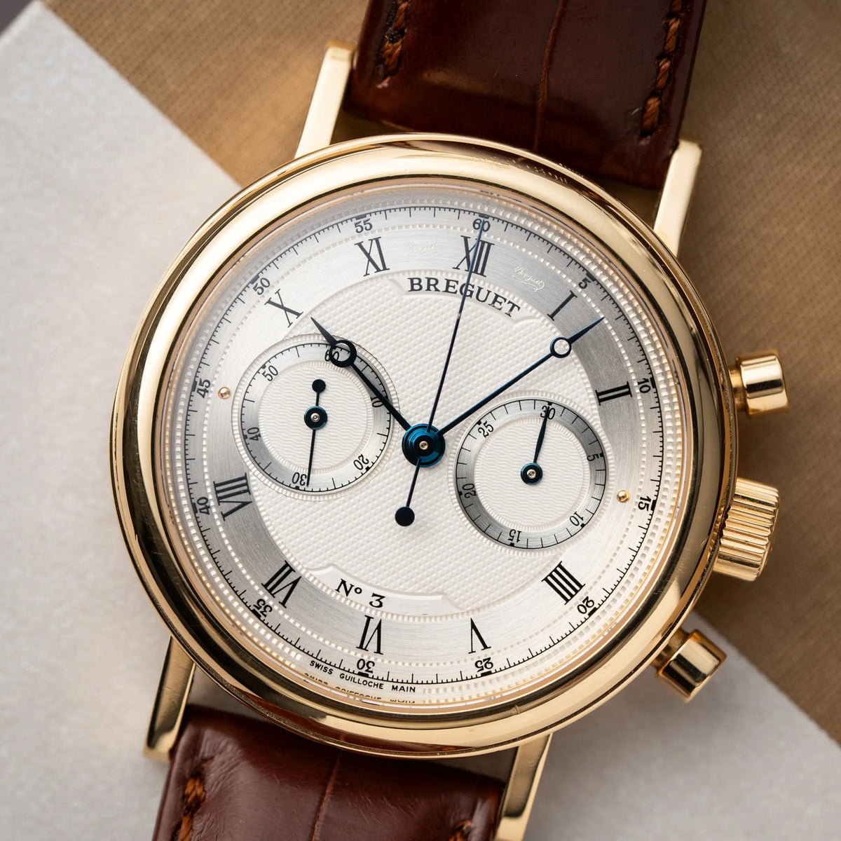 Produktfotografie zeigt den Uhrenkopf der Breguet Classique Chronograph der Referenz 5237 in Gelbgold mit silbernem guillochiertem Zifferblatt am braunem Lederband