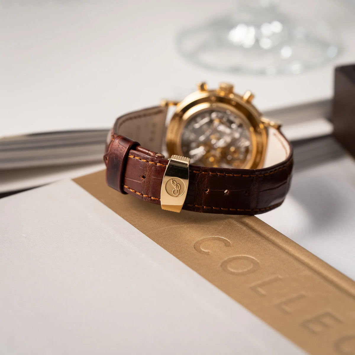 Produktfotografie des Breguet Classique Chronograph der Referenz 5237 in Gelbgold mit silbernem guillochiertem Zifferblatt am braunem Lederband zeigt die gelbgoldene Faltschliesse mit Breguet-Logo