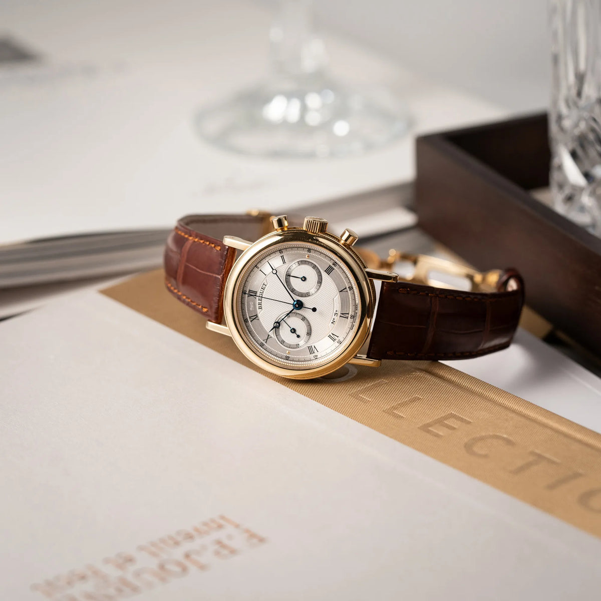 Produktfotografie des Breguet Classique Chronograph der Referenz 5237 in Gelbgold mit silbernem guillochiertem Zifferblatt am braunem Lederband