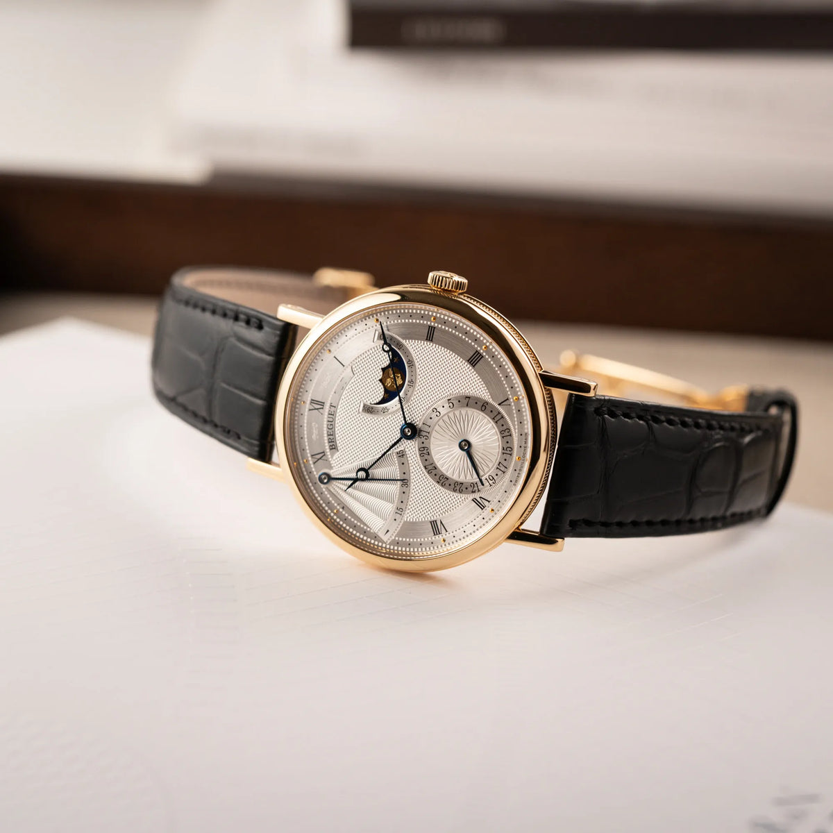 Fotografie der Breguet Classique Mondphase 7137 in Gelbgold mit silbernen, verschieden guillochiertem Zifferblatt zeigt die verschiedenen Spiegelungen auf dem Guilloche-Zifferblatt