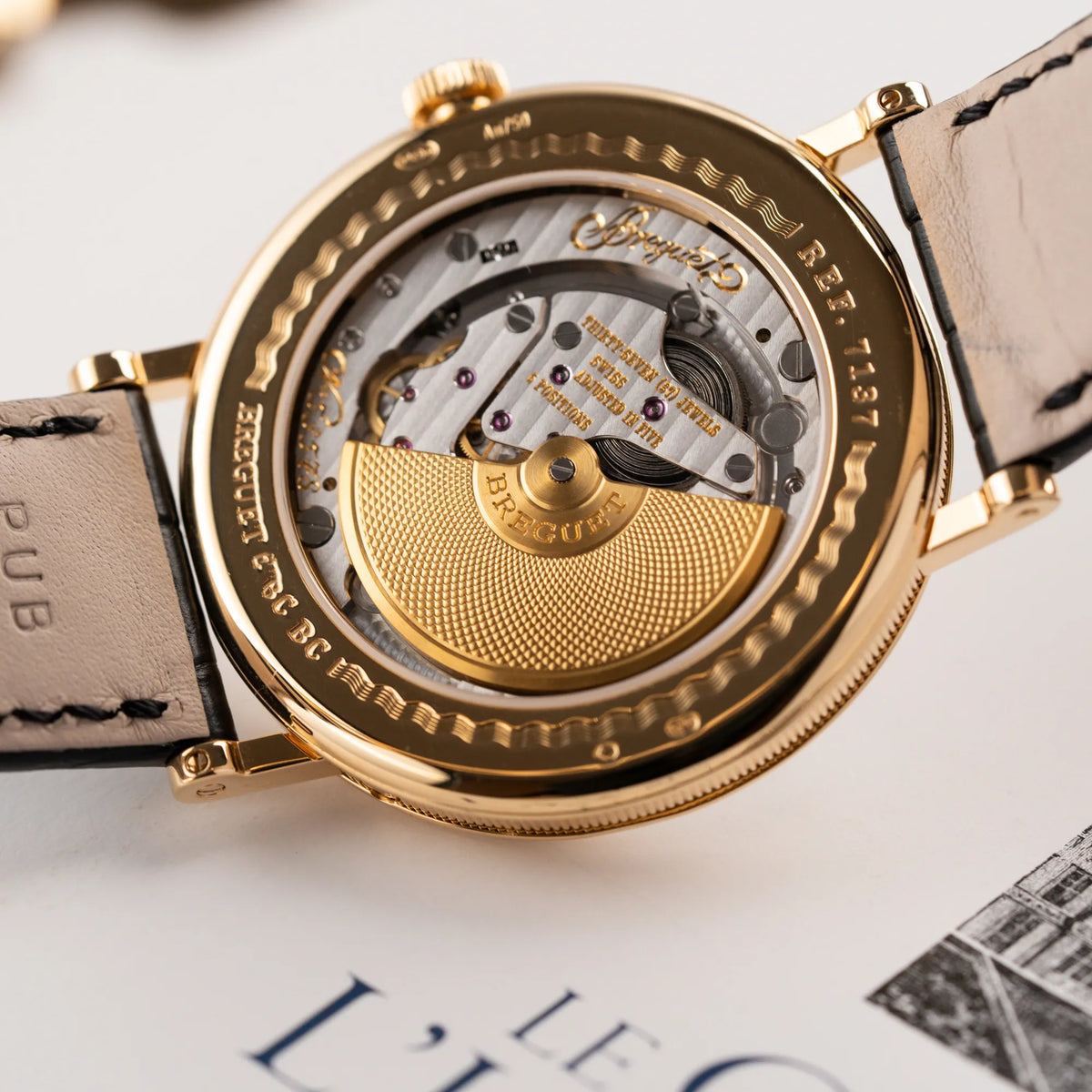 Detailaufnahme des Sichtbodens mit Blick auf den micro-Rotor der Breguet Classique Mondphase 7137 in Gelbgold mit silbernen, verschieden guillochiertem Zifferblatt