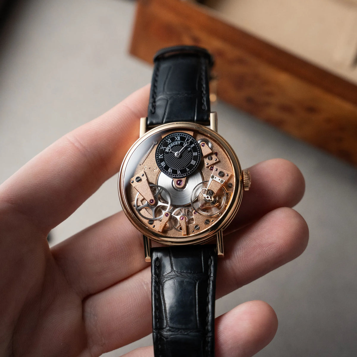 Mann hält die klassische Breguet Tradition Armbanduhr mit Rosegold-Gehäuse und schwarzem Zifferblatt in der Hand