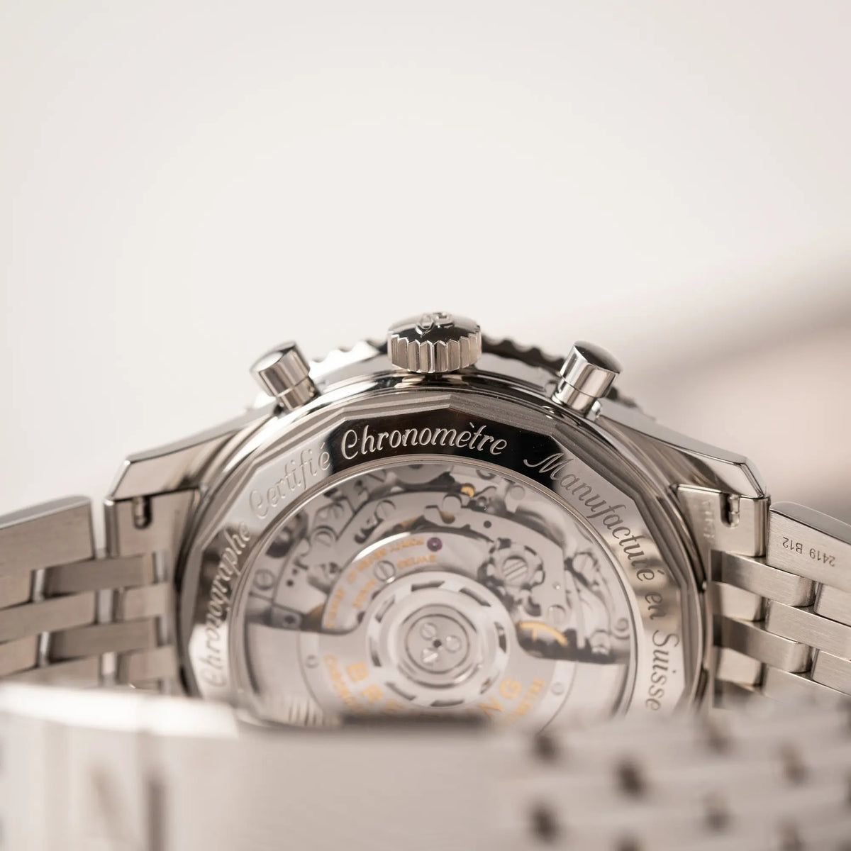 Produktfotografie der Wristshot mit der Breitling Navitimer B01 Chronograph der Referenz AB0121211B1A1 mit Reverse-Panda Zifferblatt in schwarz mit weißen Hilfszifferblätter zeigt die Aufzugskrone und den Gehäuseboden aus Sichtglas