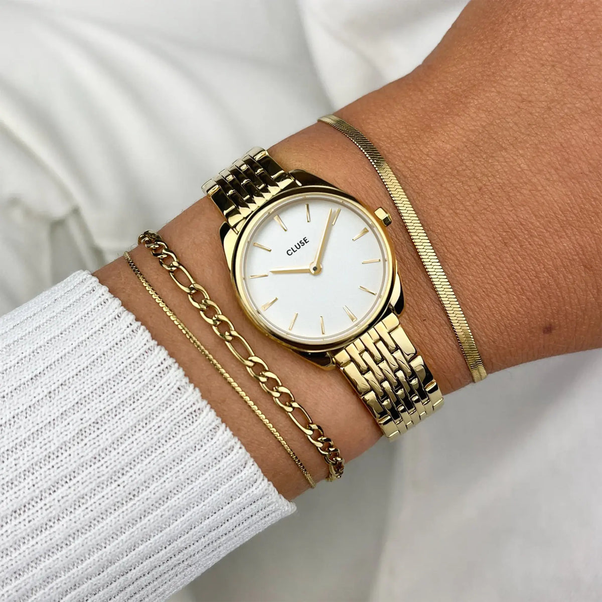 Wristshot mit der goldfarbenen Cluse Damenuhr Feroce Mini CW11705 mit rundem Gehäuse, einem weißem Zifferblatt und einem feingliedrigem, goldfarbenem Uhrenarmband