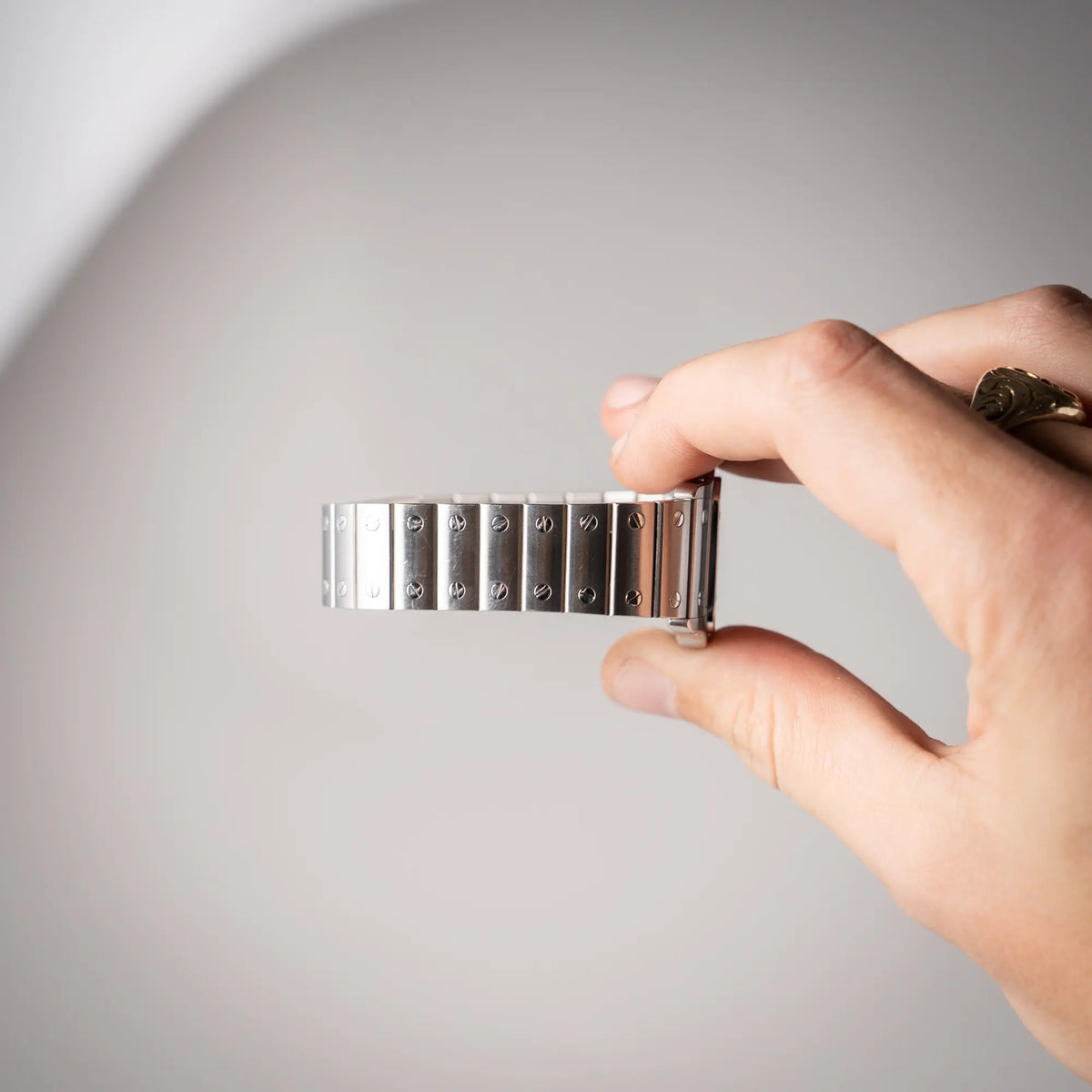 Mann hält die Cartier Santos Galbée 2913 in Edelstahl mit weiß-silbernem Zifferblatt am Stahlband mit der klassischen Cartier-Schrauben-Optik in seiner Hand und präsentiert den nicht-vorhandenen Stretch des Armbands