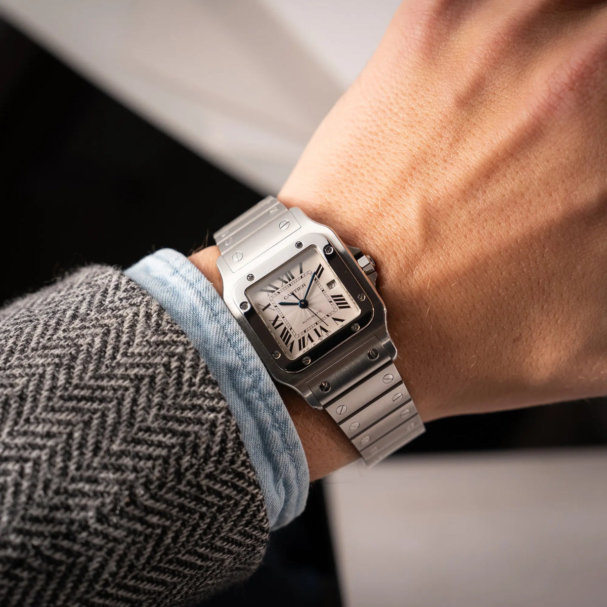 Mann trägt die Cartier Santos Galbée 2913 in Edelstahl mit weiß-silbernem Zifferblatt am Stahlband mit der klassischen Cartier-Schrauben-Optik an seinem Handgelenk