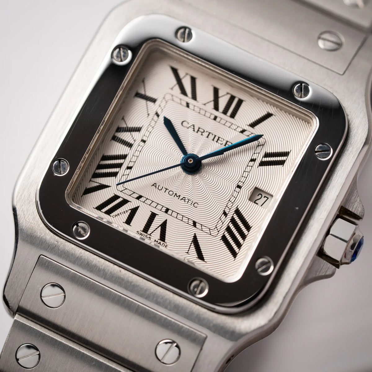 Detailaufnahme der Cartier Santos Galbée 2913 in Edelstahl mit weiß-silbernem Zifferblatt am Stahlband mit der klassischen Cartier-Schrauben-Optik mit Fokus auf dem gebläutem Zeigersatz