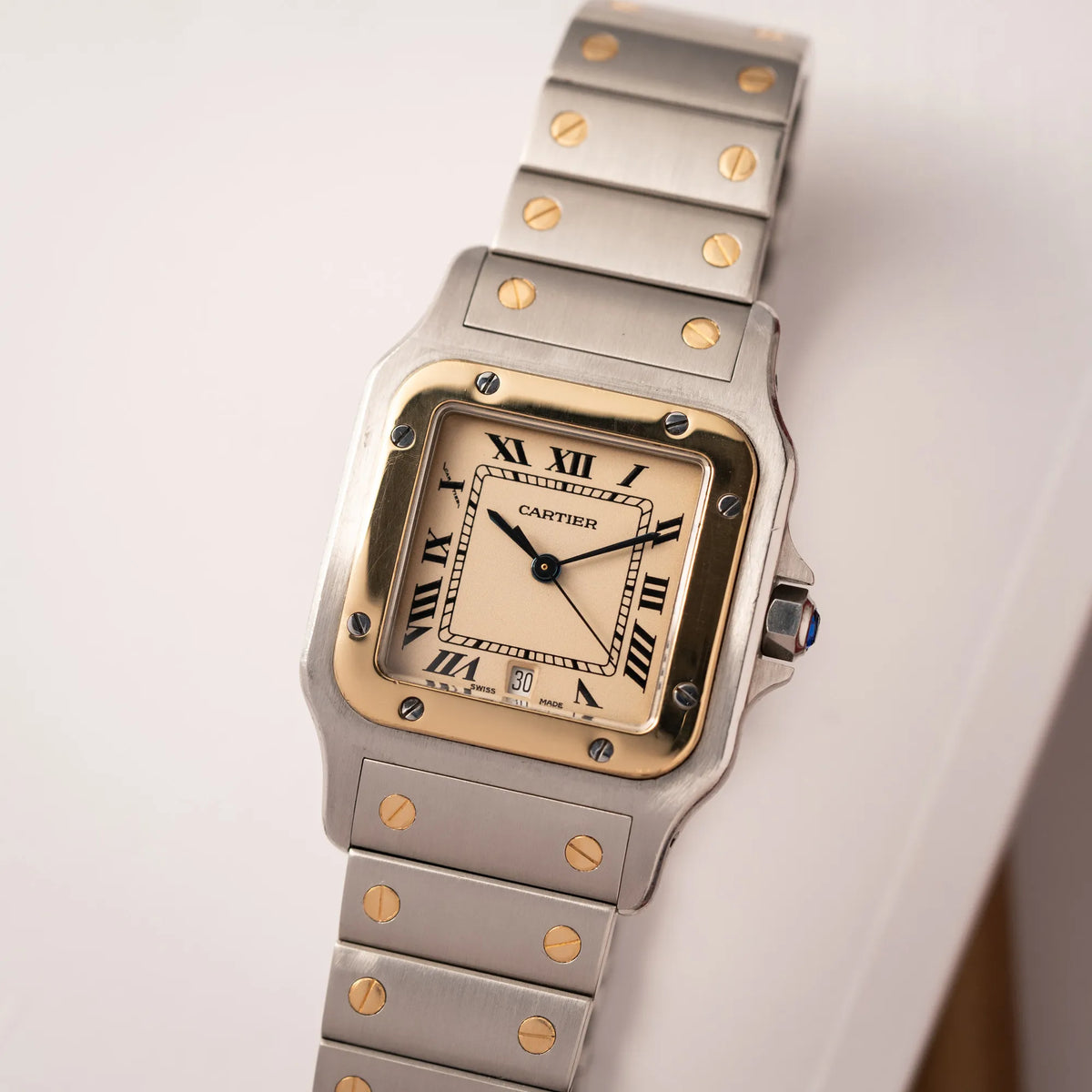 Produktfotografie zeigt den Draufblick auf die Cartier Santos Galbee BiColor der Referenz 187901 mit Stahl-Gold-Gehäuse am Stahlband mit dem Cartier-typischen Schrauben, die ebenfalls in Gelbgold gehalten sind, und einem cremfarbenen Zifferblatt mit klassischen römischen Indizes