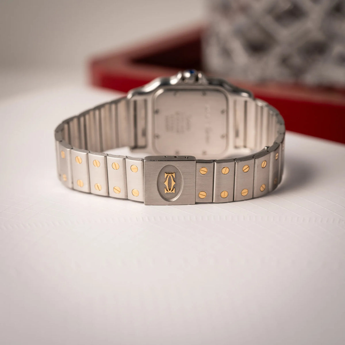 Produktfotografie zeigt das Armband und die Schliesse der Cartier Santos Galbee BiColor der Referenz 187901 mit Stahl-Gold-Gehäuse am Stahlband mit dem Cartier-typischen Schrauben, die ebenfalls in Gelbgold gehalten sind, und einem cremfarbenen Zifferblatt mit klassischen römischen Indizes
