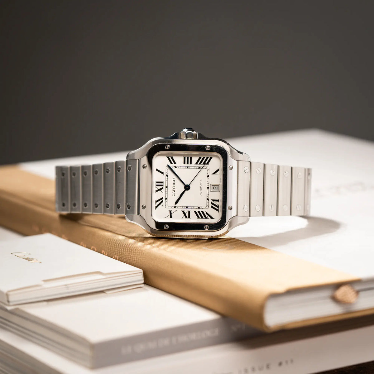 Produktfotografie der Cartier Santos de Cartier als großes Modell der Referenz WSA0018 mit dem klassischen weißen Zifferblatt und römischen Indizes zeigt die Uhr mit den polierten und satinierten Oberflächen