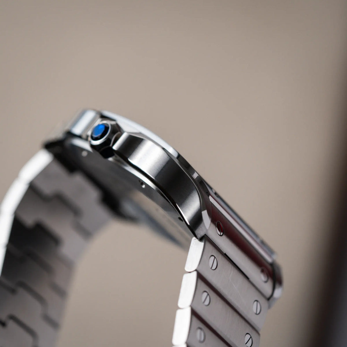 Detailaufnahme eines der Bandanstöße der Cartier Santos de Cartier als großes Modell der Referenz WSA0018 mit dem klassischen weißen Zifferblatt und römischen Indizes zeigt die verschiedenen Phasen mit den polierten und satinierten Oberflächen