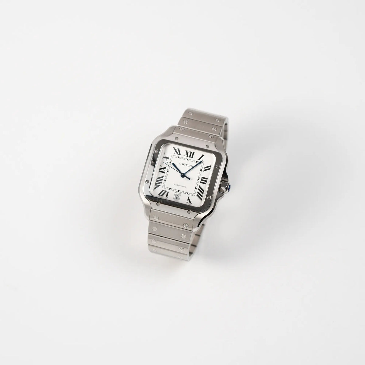 Leicht schräge Ansicht der Cartier Santos de Cartier als großes Modell der Referenz WSA0018 mit dem klassischen weißen Zifferblatt und römischen Indizes zeigt die Uhr mit den polierten und satinierten Oberflächen