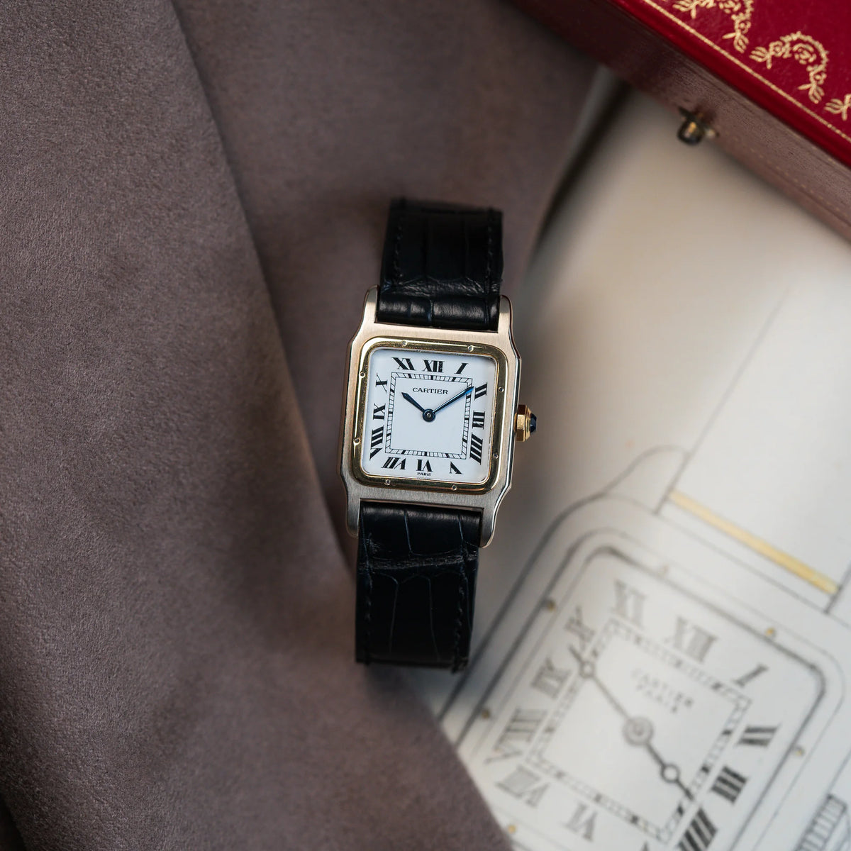 Produktfotografie der Cartier Santos Dumont "Deux Ors" mit weißem Paris Dial mit einer Zeichnung als Hintergrund