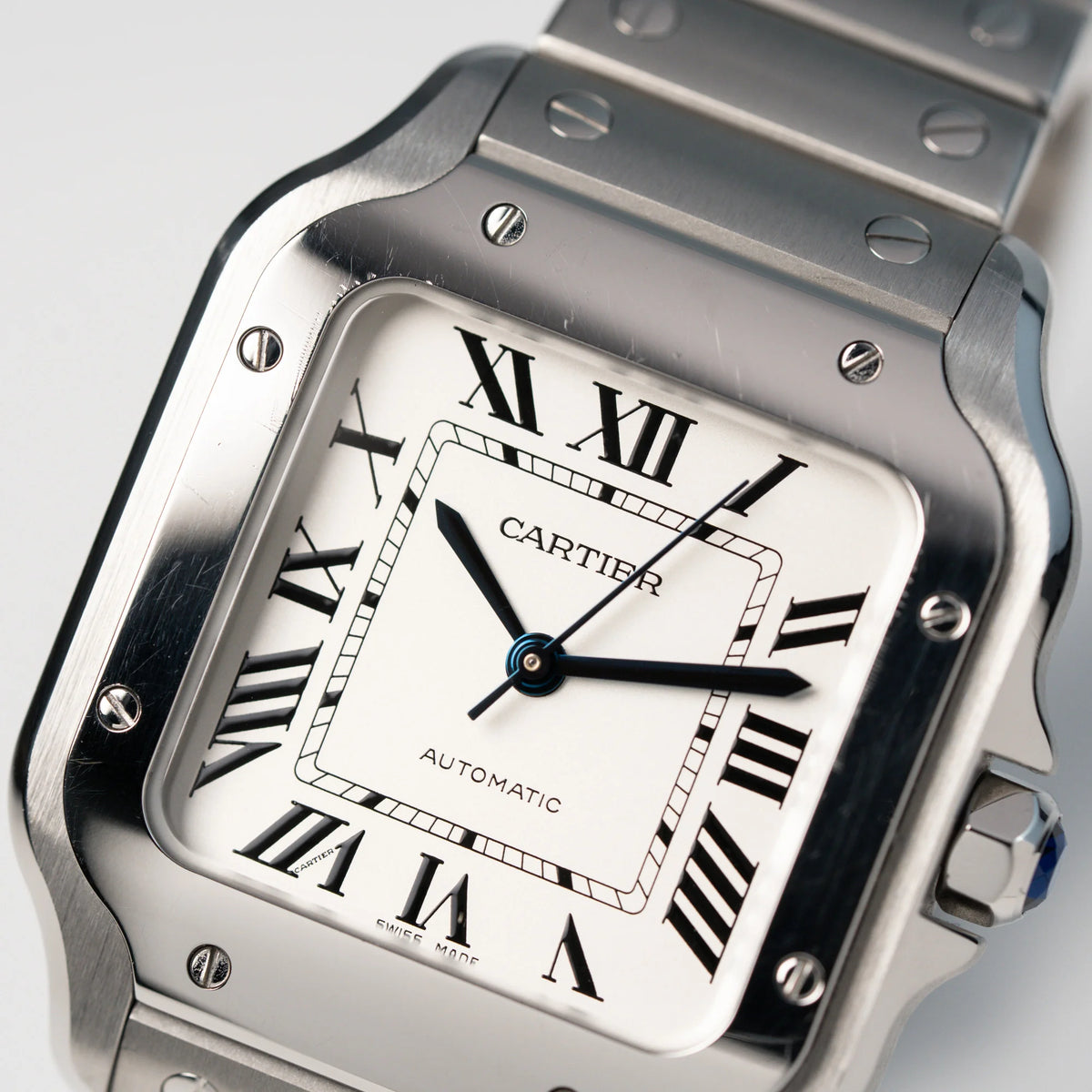 Detailaufnahme des Zifferblatts und der Lünette der Cartier Santos Medium mit dem klassischen weißen Zifferblatt mit römischen Indizes