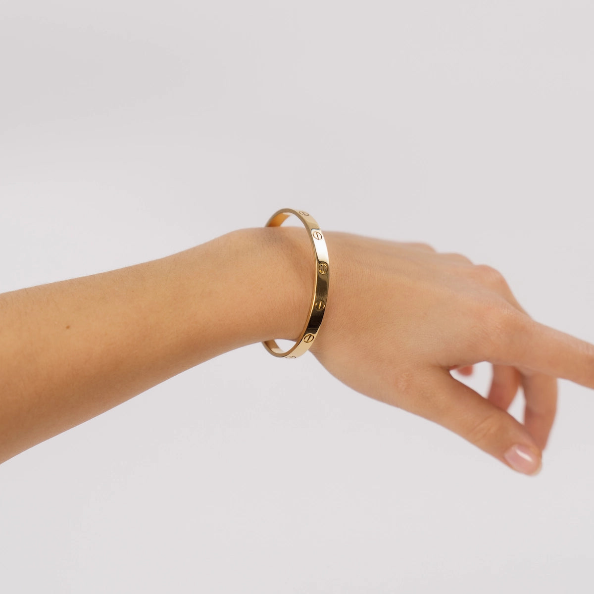 Frau trägt Cartier Love Bracelet in Gelbgold am Handgelenk