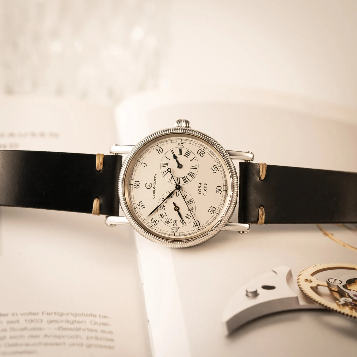 Produktfotografie der Chronoswiss Regulator Tora C123 mit weißem Zifferblatt mit zwei symmetrisch angeordneten Hilfszifferblättern mit römischen Indizes