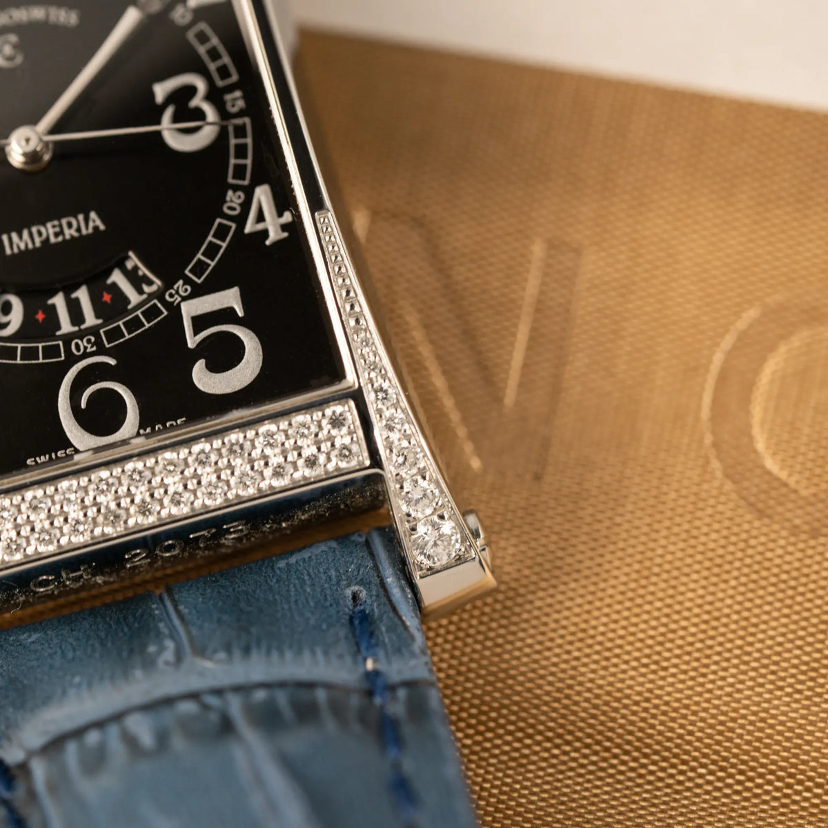 Detailaufnahme des unteren rechten Bankanstoßes der Chronoswiss Imperia Constanze mit diamantbesetzten-Stahlgehäuse mit schwarzem Zifferblatt an einem petrol-blauem Lederband