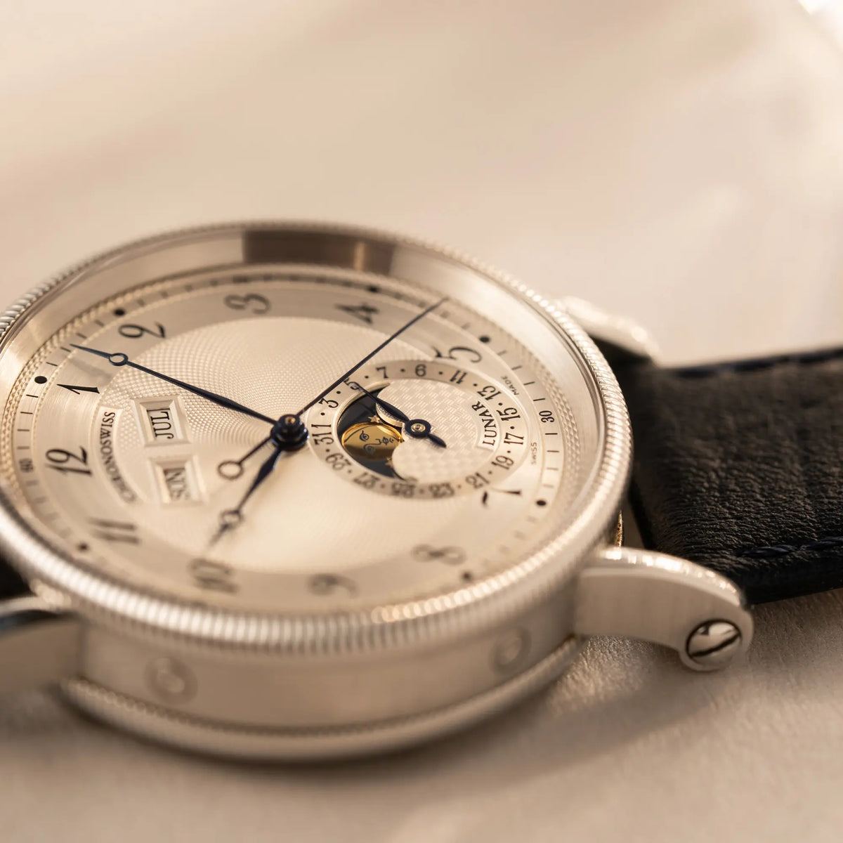 Detailaufnahme der Chronoswiss Klassic Luna Mondphase CH9323 mit silbernem, guillochiertem Zifferblatt mit Kalenderanzeige auf 12 Uhr und einer Mondphase-Anzeige bei 6 Uhr mit Fokus auf der Mondphase