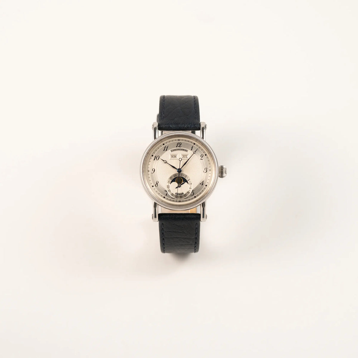 Frontale Ansicht der Chronoswiss Klassic Luna Mondphase CH9323 mit silbernem, guillochiertem Zifferblatt mit Kalenderanzeige auf 12 Uhr und einer Mondphase-Anzeige bei 6 Uhr