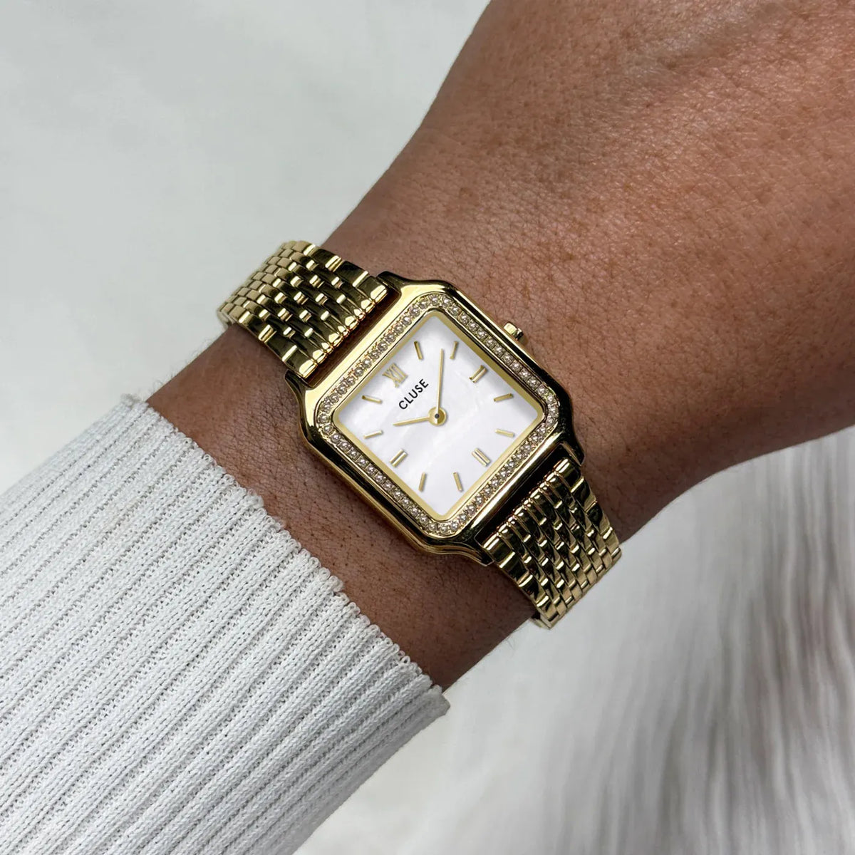 Wristshot mit der goldfarbenen Cluse Gracieuse Damenuhr CW11826 mit weißem Zifferblatt und einem Glassteinbesatz auf der Lünette