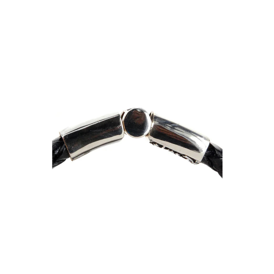 Detailaufnahme des Verschluss-Mechanismus des schwarzen, geflochtenen Lederarmbands mit glattem Silberverschluss und einer zentralen Lielie als Design-Highlight des Verschlusses