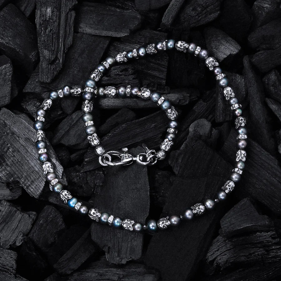 Produktofografie der Elfcraft Halskette mit schwarzen Perlen und silbernen Elementen im Totenkopf, während das Collier auf schwarzer Holzkohle liegt