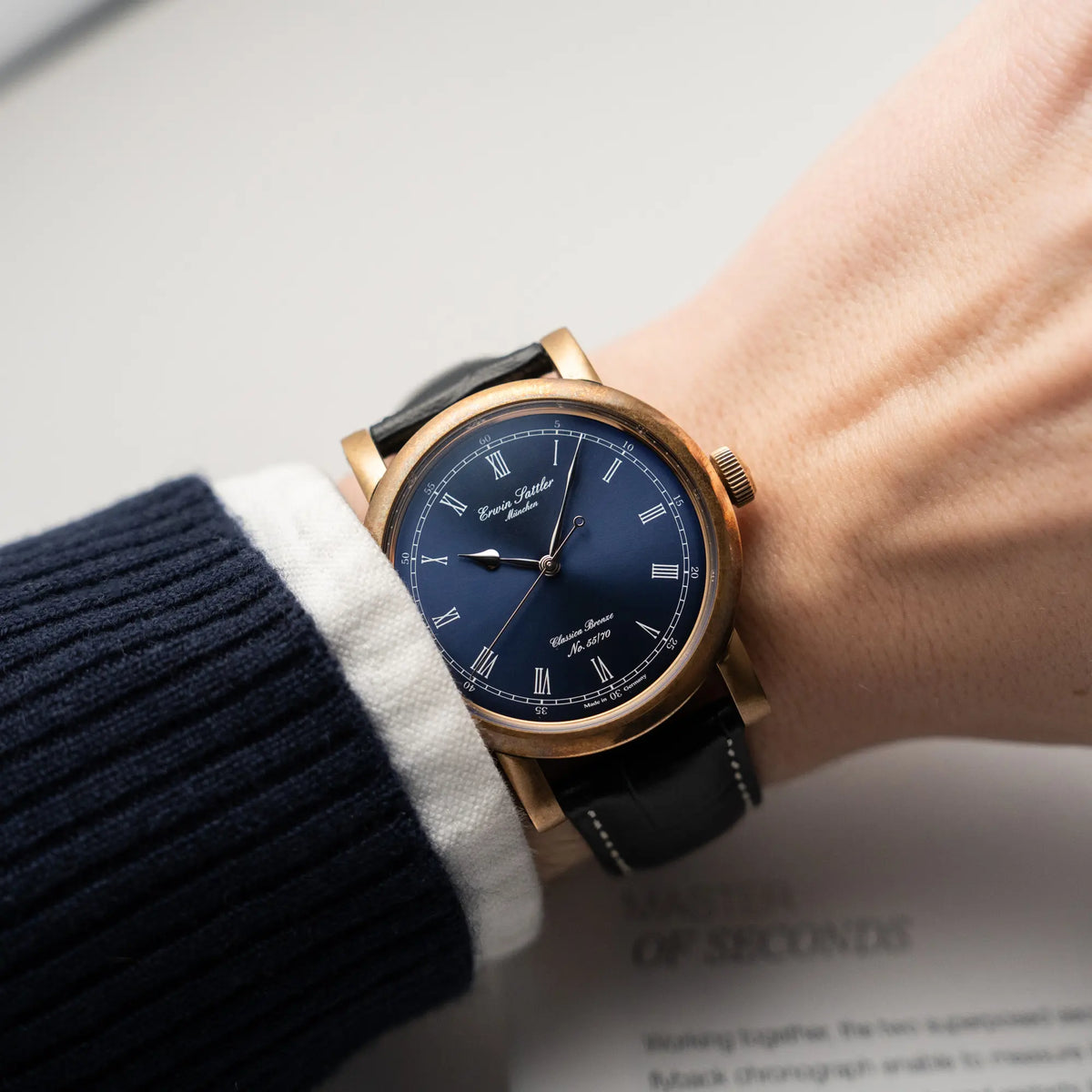 Mann trägt die limitiertenErwin Sattler Classica Armbanduhr in einem Bronze-Gehäuse mit blauem Zifferblatt an seinem Handgelenk