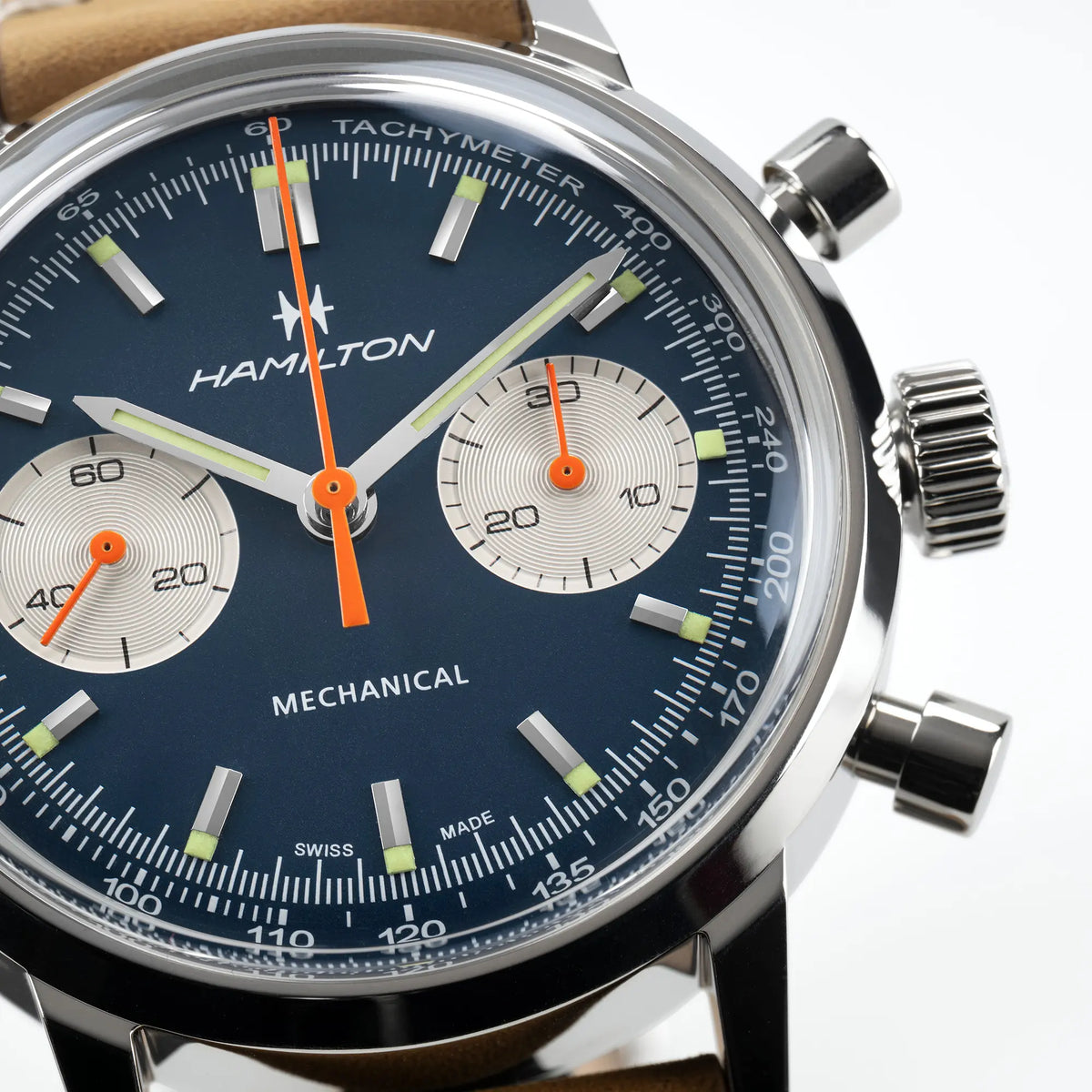 Detailaufnahme des Hamilton American Classic Intra-matic Chronographen mit blauem Zifferblatt und orangen Details an einem hellbraunen Lederband mit zusätzlichem Mesh-Edelstahl-Armband