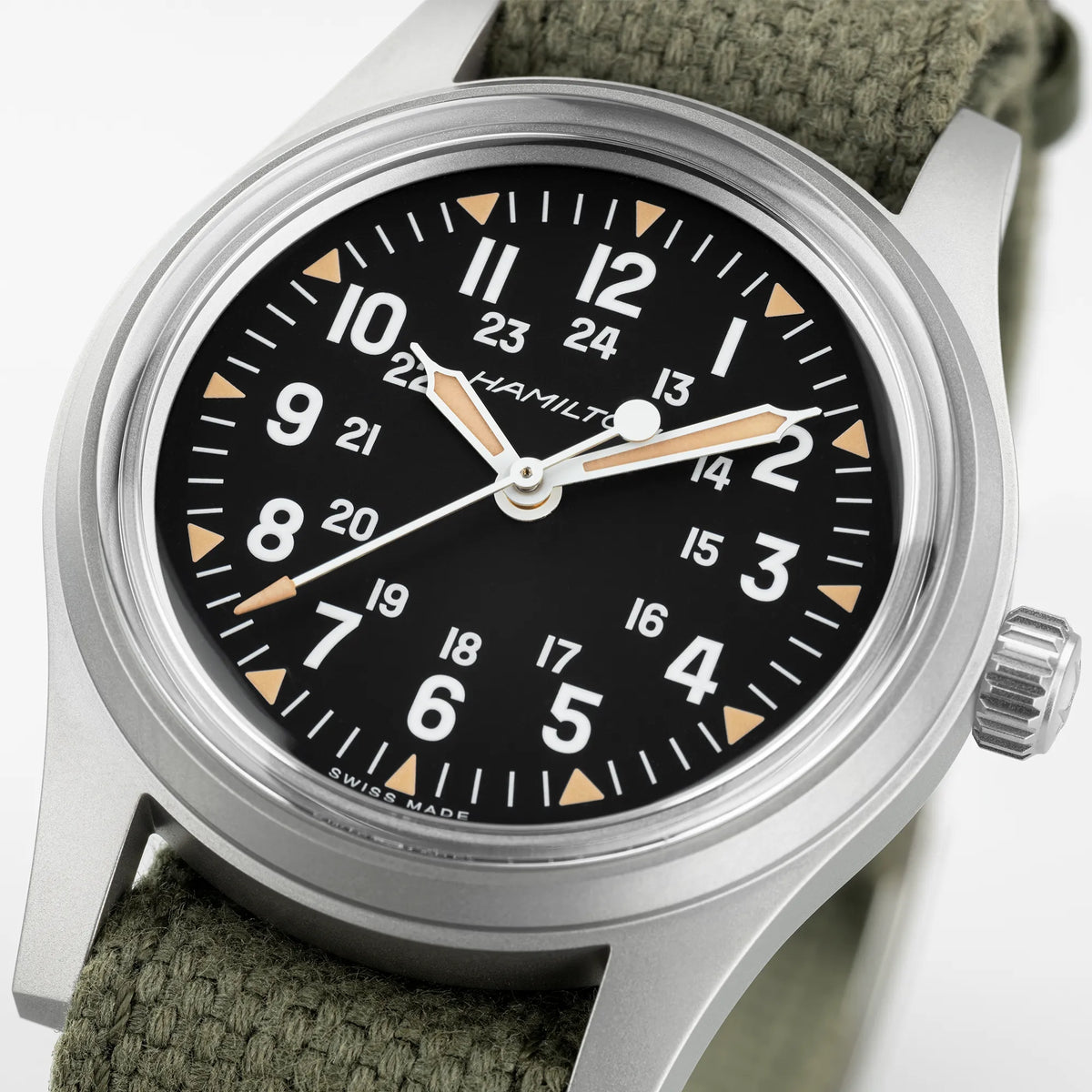 Detailansicht mit Fokus auf dem Zeigersatz der Hamilton Khaki Field Mechanical H69399930 mit schwarzem Zifferblatt im Vintage-Charakter mit Indizes in weiß und beige an einem khaki-farbenem Nato-Band